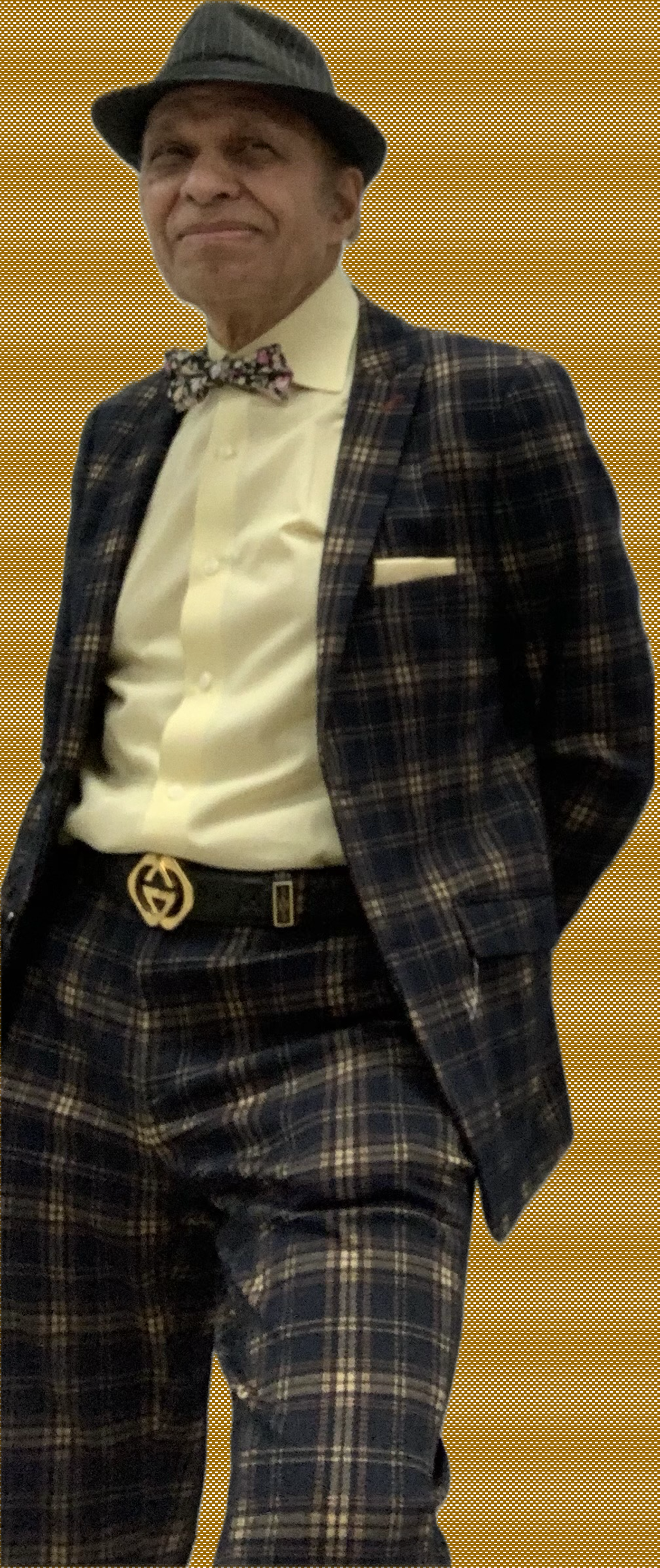 Dr. Magdy Bayoumi wearing a suit and hat standing against a wall