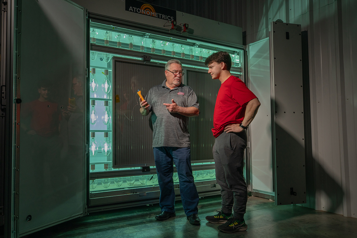 Picture of Dr. Terrence Chambers and Wyatt Stoute in front of some photovoltaic panels.